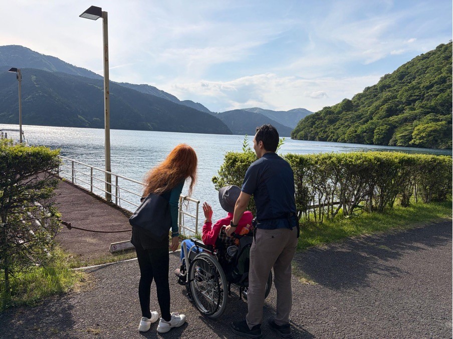 芦ノ湖湖畔にいる車椅子の男性と家族とヘルパー